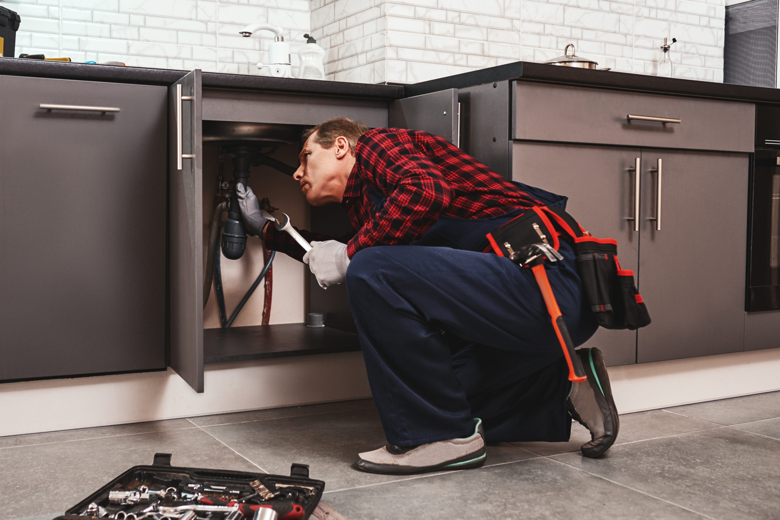 Fitting repair with wrench. Seniour handyman repairing washbasin